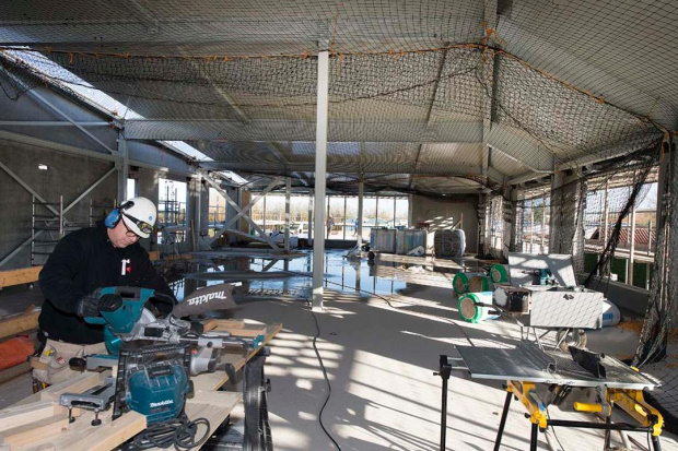 Man die balken aan het afkorten is op een bouwplaats